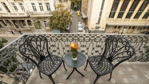 Un balcón con dos sillas de metal y una mesita, con un florero y flores.