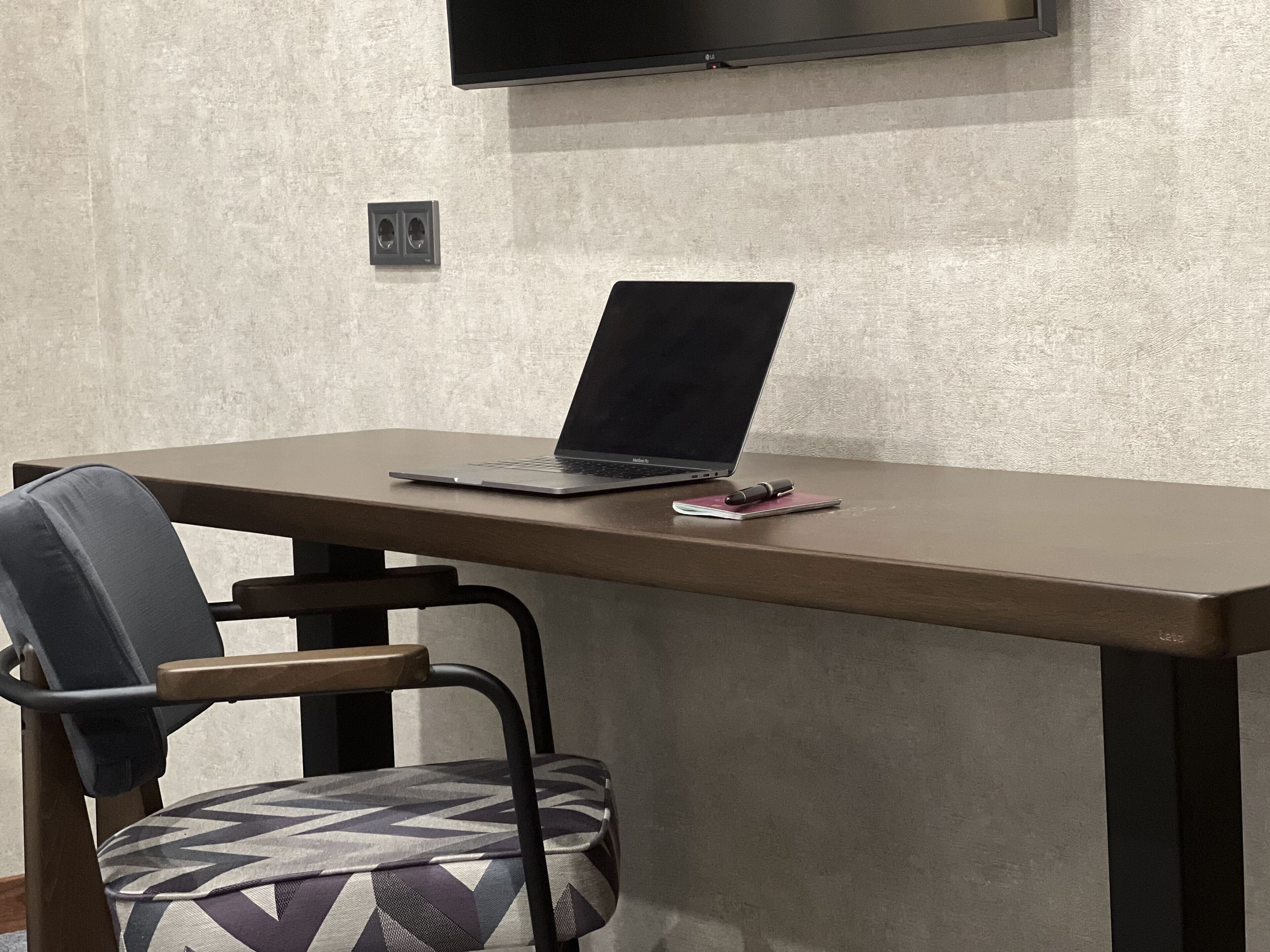 A laptop on a table with a notebook and pen beside it.