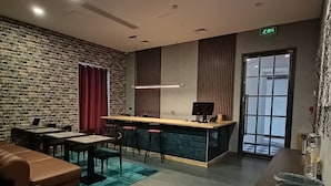 Una cocina moderna con una isla central, una zona de comedor con pared de ladrillo decorativa y un rincón de estar con sofá de cuero.
