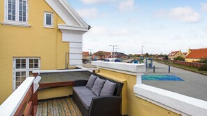 A balcony with a wicker sofa and a view of a train station. - 3 bedroom beautiful home in Skagen (Skagen)