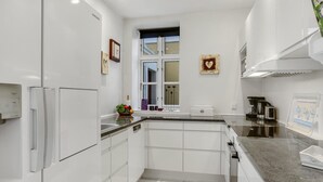 A modern kitchen with white cabinetry, a built-in oven, and a window with a view. - 3 bedroom beautiful home in Skagen (Skagen)