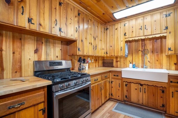 Una cocina con armarios de madera, estufa de acero inoxidable y encimera blanca.