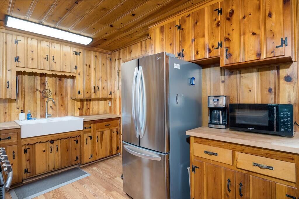 A kitchen with wooden cabinets, stainless steel appliances, and a microwave.