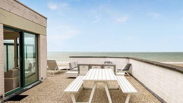 Enjoy a tranquil moment on this outdoor space with a table and chairs overlooking the beach.