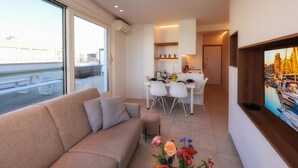 Ein modernes Wohnzimmer mit einer Couch, einem Essbereich und einer Küche im Hintergrund.