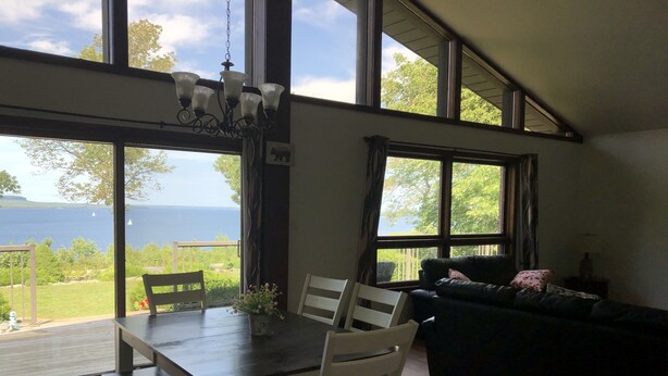 Un coin repas avec une table et des chaises, un canapé et de grandes fenêtres donnant sur la mer.