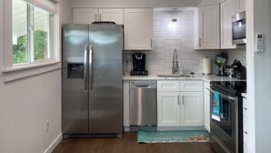 A compact kitchen with white cabinets, stainless steel appliances, a dishwasher, and a microwave. - 🏖 🏐 Upstairs Valley Beach Escape Apartment 🛹 💦 🏀 (Spokane Valley)