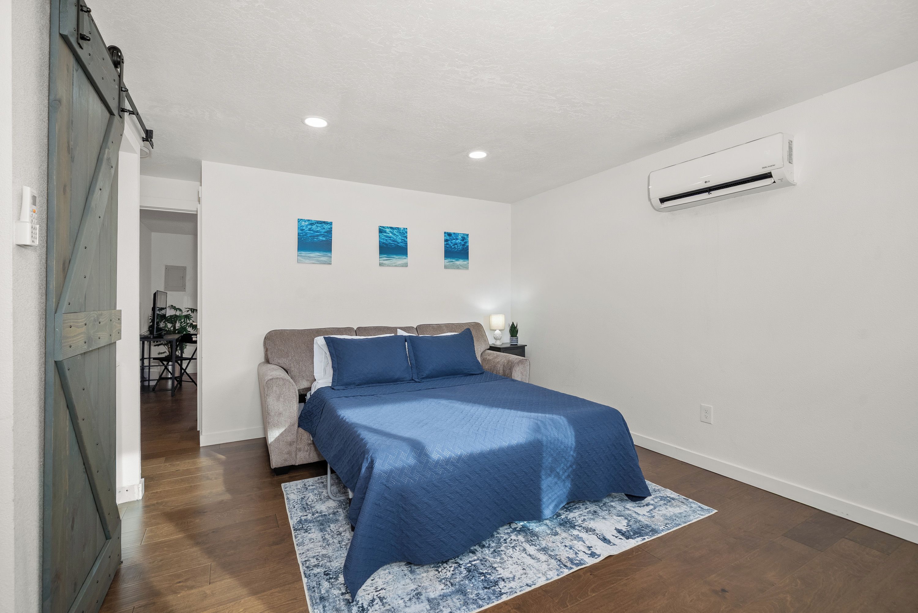 Bright, cozy bedroom with blue accents, barn door, and mini-split AC