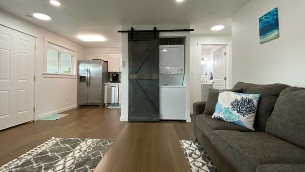 A modern living room with a gray sofa, a patterned rug, and a kitchen in the background. - 🏖 🏐 Upstairs Valley Beach Escape Apartment 🛹 💦   🏀 (Spokane Valley)