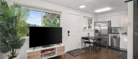 Bright modern living area with full kitchen, big windows, and cozy dining nook