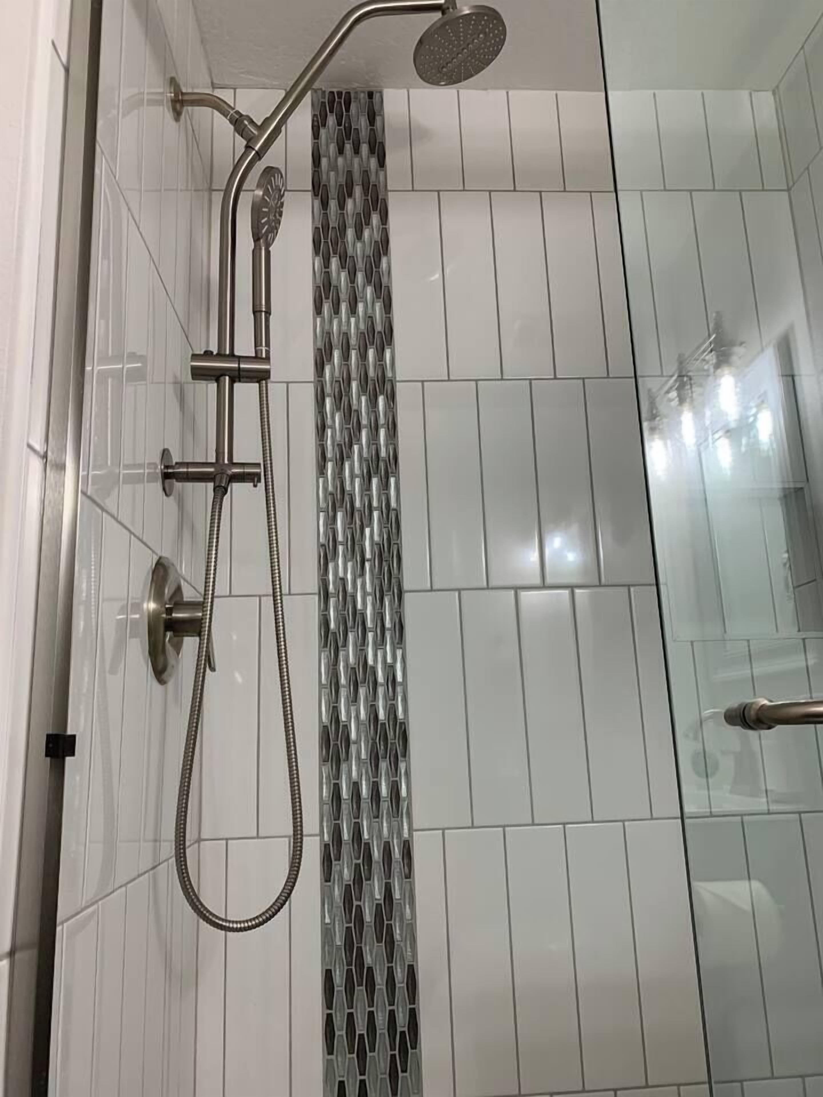 Une douche équipée d’un pommeau de douche à main et d’un pommeau de douche mural en forme de pluie.