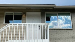 A two-story building with a white front door, a balcony with white railings, and a brick facade. - 🏖 🏐 Upstairs Valley Beach Escape Apartment 🛹 💦 🏀 (Spokane Valley)