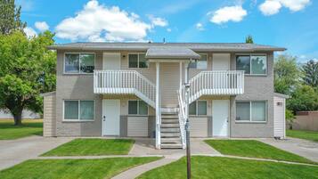A two-story apartment building with a central staircase, a small porch, and a garage.