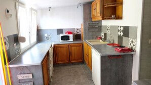 A compact kitchen with wooden cabinets, a microwave, a sink, and a tiled backsplash.
