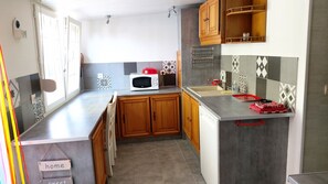 A compact kitchen with wooden cabinets, a microwave, a sink, and a tiled backsplash.