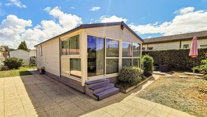 Ein kleines, eingeschossiges Haus mit einem großen Glasfenster und einer kleinen Veranda.
