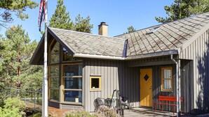 A wooden cabin with large windows, a chimney, and a flagpole. - 4 bedroom stunning home in Hebnes (Hebnes)