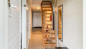 A hallway with a wooden staircase, a fire extinguisher, and a door with keys hanging on it.