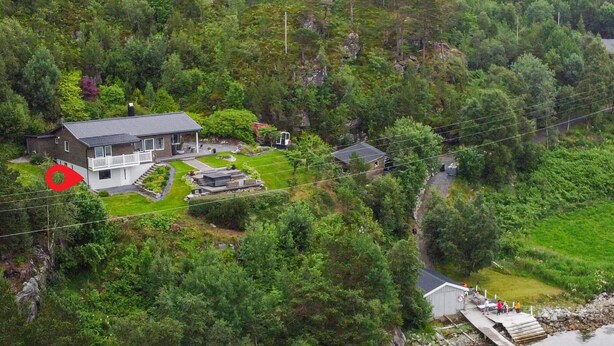 A house with a front deck, a small garden, and a dock by a body of water.