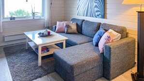 A cozy living room with a grey sofa, a white coffee table, and a painting on the wall.