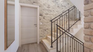 Una escalera con barandilla de metal negro, una puerta de madera y un muro de ladrillo.