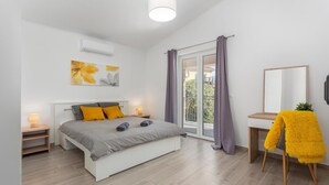 Un dormitorio moderno con cama, mesitas de noche, un espejo y vistas al exterior.