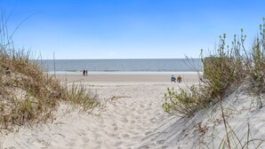 A sandy beach with a clear sky and calm sea. - Cheerful 3BR/2BA - just steps to the beach! (Oak Island)