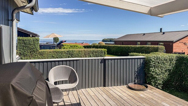 A covered outdoor area with a wooden deck, a chair, and a grill. - Pet friendly home in Hejls with WiFi (Hejls)