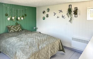 Un dormitorio con cama, una planta colgante, decoración en la pared y un radiador.