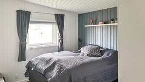 A bedroom with a bed, curtains, a shelf with decorative items, and a window. - Pet friendly home in Hejls with WiFi (Hejls)
