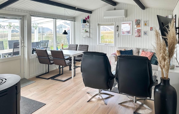Et moderne interiør med et spiseområde, sorte stole, et hvidt bord og en sofa.