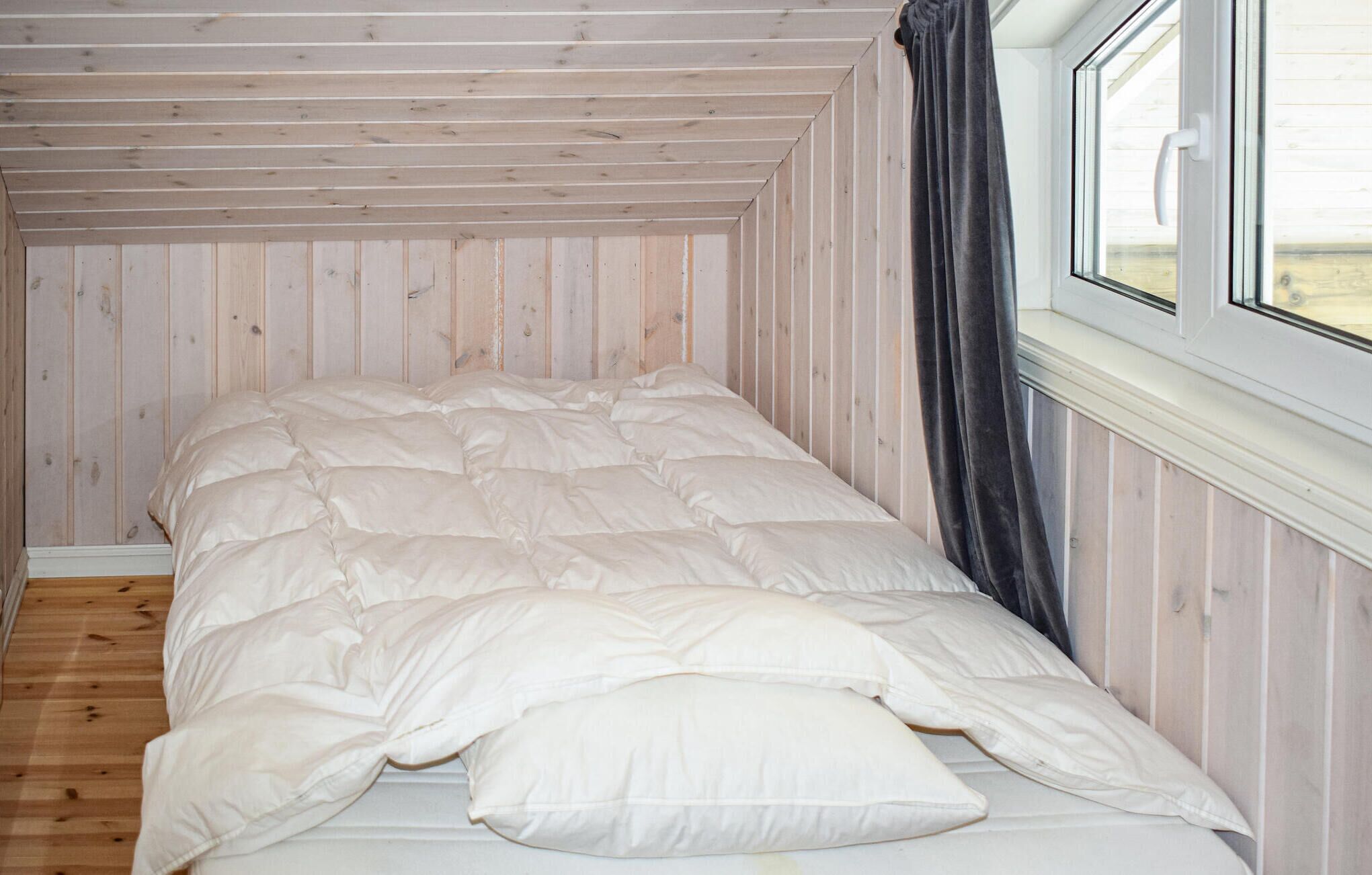 A single bed in a room with wooden walls and a sloped ceiling.