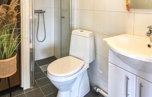 A bathroom with a toilet, shower, sink, and a potted plant. - Cozy home in Brøttum with kitchen (Brøttum)