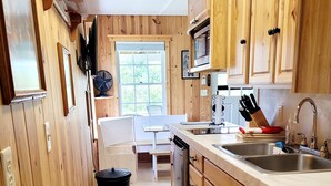 A kitchen with wooden cabinets, a sink, a microwave, and a window.
