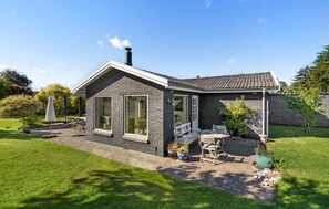 A modern house with a brick exterior, large windows, and a patio area with outdoor furniture. - 3 bedroom stunning home in Malling (Malling)