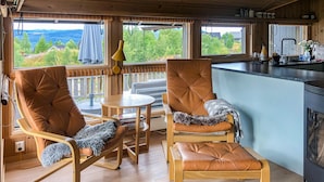 A cozy cabin interior with two leather chairs, a small round table, and a view of the outdoors.