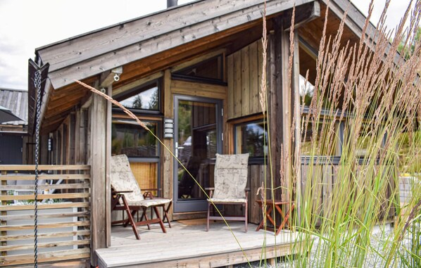 Een houten chalet met veranda, twee stoelen en een tafel.