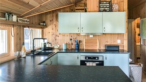 A modern kitchen with wooden walls, a black countertop, and stainless steel appliances.
