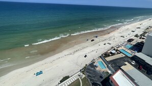 Ein Strand mit Poolbereich, Parkplatz und Blick aufs Meer.