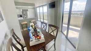 Ein Essbereich mit Tisch für vier Personen, eine Küche im Hintergrund und ein Balkon mit Blick.