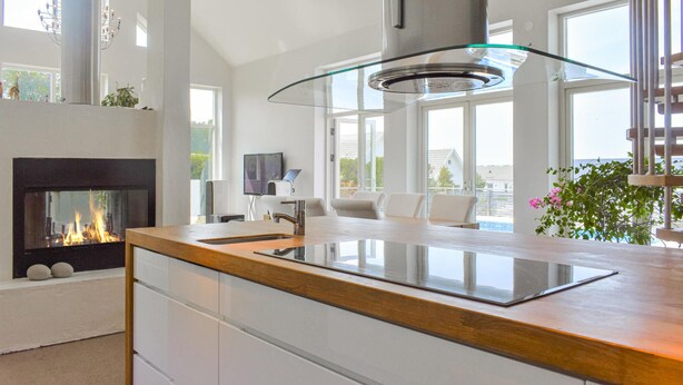 A modern kitchen with a glass cooktop, a built-in fireplace, and large windows offering a view of the outdoors. - 4 bedroom stunning home in Ramdala (Ramdala)