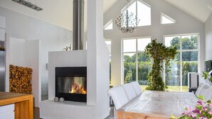 A modern living room with a fireplace, white furniture, and large windows offering a view of the outdoors. - 4 bedroom stunning home in Ramdala (Ramdala)