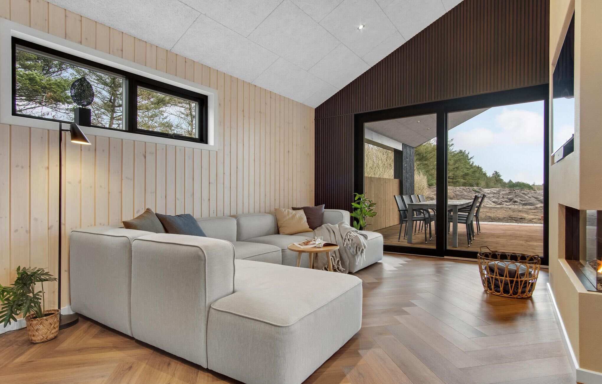 A modern living room with a sectional sofa, a small round table, and a view of the outdoors.