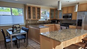 A modern kitchen with granite countertops, wooden cabinets, and stainless steel appliances. - Modern, spacious four-bedroom home on quiet street (Seattle)