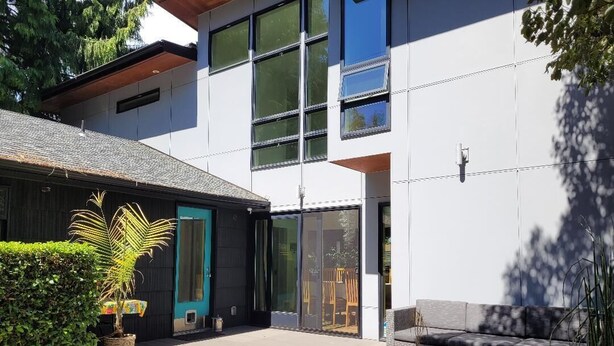 A modern house with a patio, a door with a teal frame, and a large window. - Modern, spacious four-bedroom home on quiet street (Seattle)