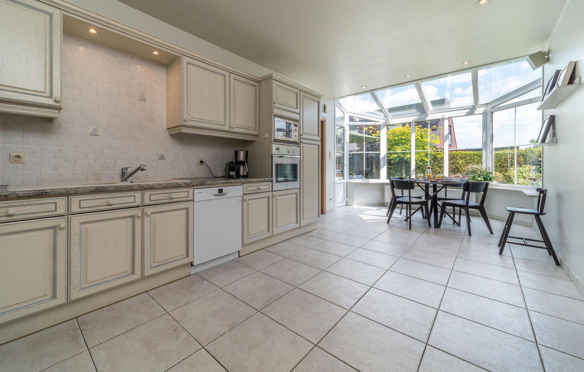 A spacious kitchen with a dining area, large windows, and a view of the outdoors.