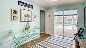 A room with a coastal living theme, featuring a dining area with green chairs, a small table with a ship model, and framed artwork on the walls. - 3/2 HEATED POOL HOME ON DEEP WATER CANAL (Crystal River)