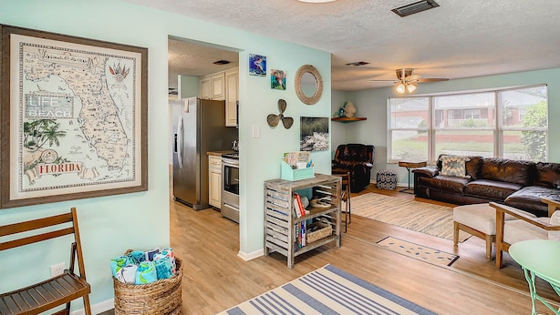 A spacious living room with a large window, a kitchen area, and a dining area. - 3/2 HEATED POOL HOME ON DEEP WATER CANAL (Crystal River)