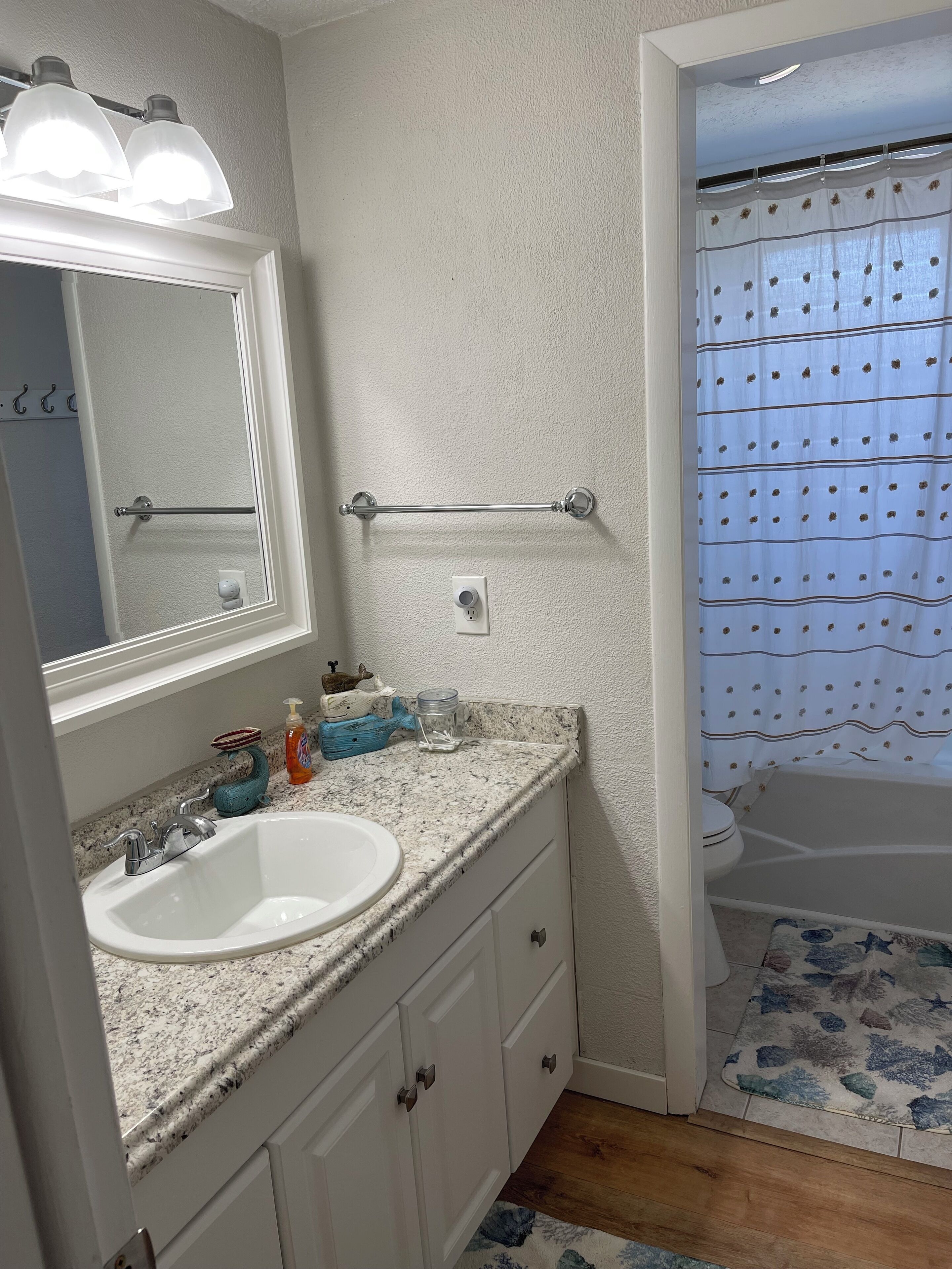 A bathroom with a white sink, mirror, and vanity, a towel rack, and a shower curtain.