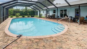 A covered swimming pool with a brick deck, a patio area with outdoor furniture, and a house in the background. - 3/2 HEATED POOL HOME ON DEEP WATER CANAL (Crystal River)